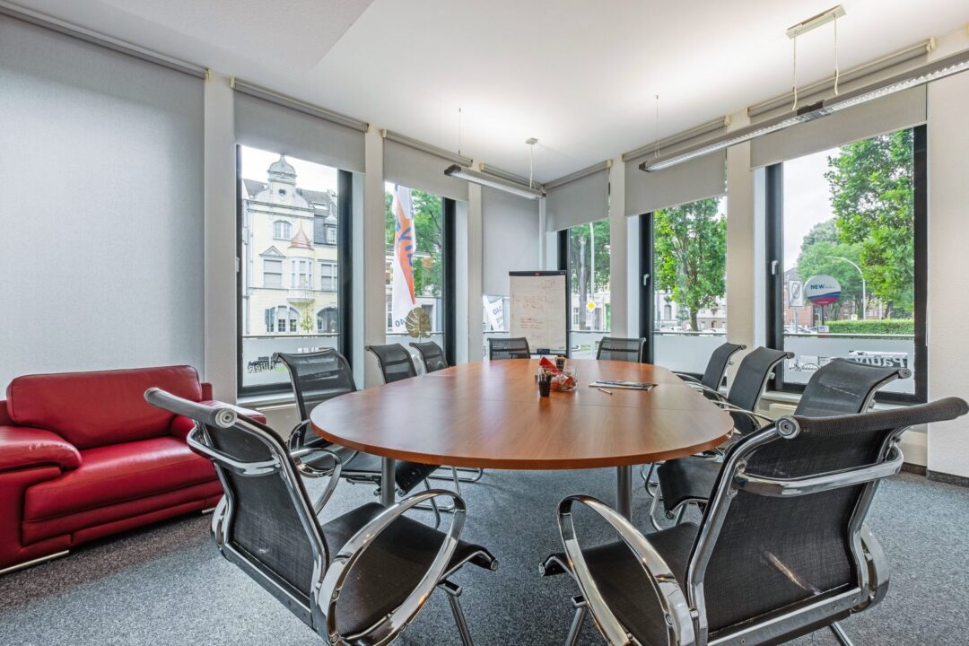 Besprechungsraum mit rundem Tisch und großen Fenstern im Büro von Wolfgang Pauly Immobilien in Mönchengladbach